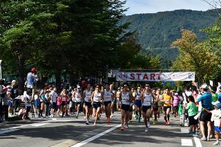 沿道には沢山の観客の方が選手達のスタートを見守って応援しており、上武大学駅伝部のみなさんを先頭にスタートし、その後ろに選手の皆さんが続いて走っているスタート地点の写真
