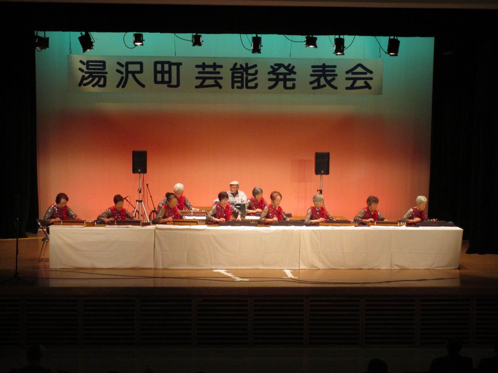 舞台の上で大正琴を演奏する大正琴花水木の会のメンバーの写真