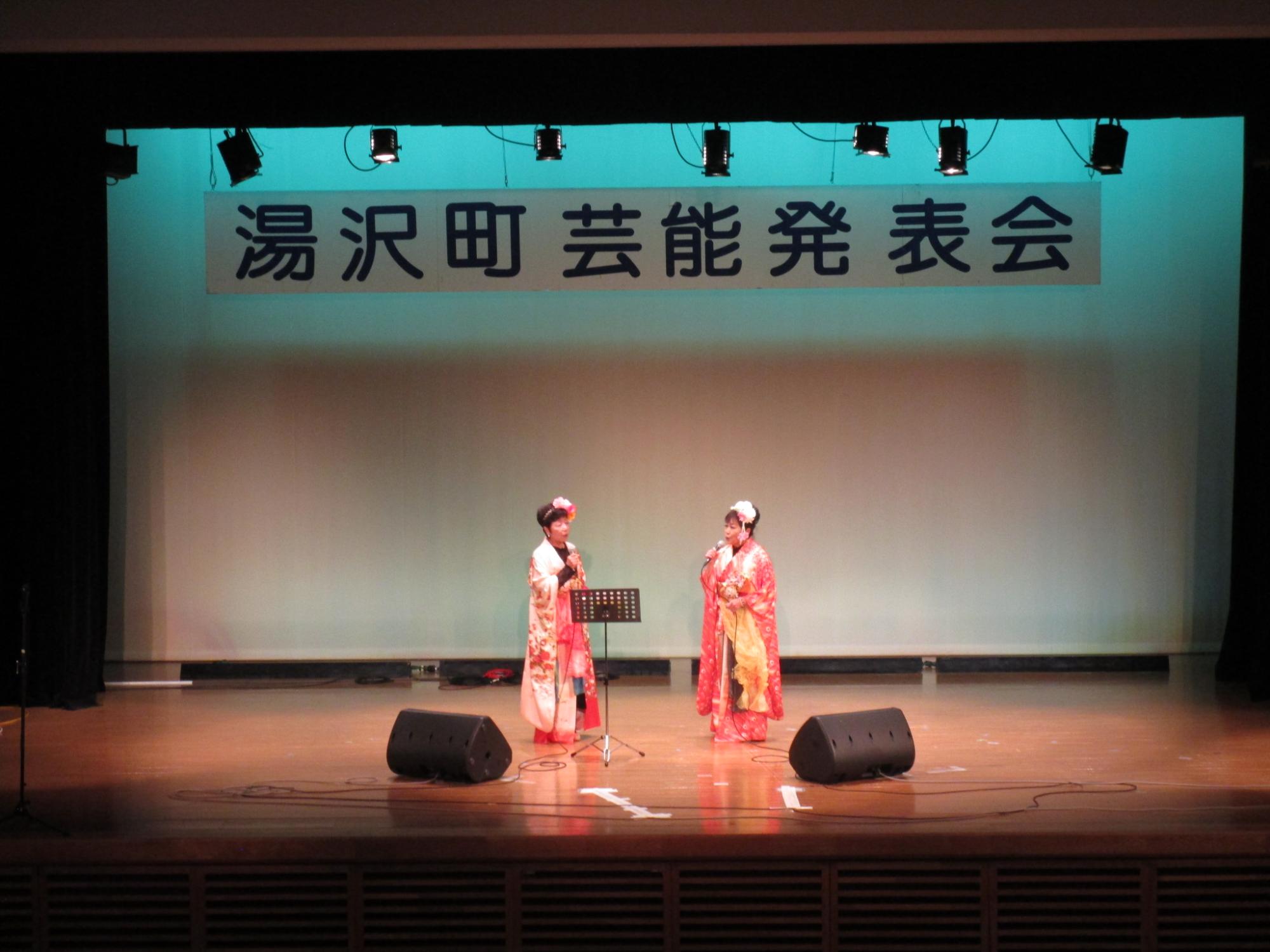 舞台で歌唱する雪国演芸友の会のメンバーの写真