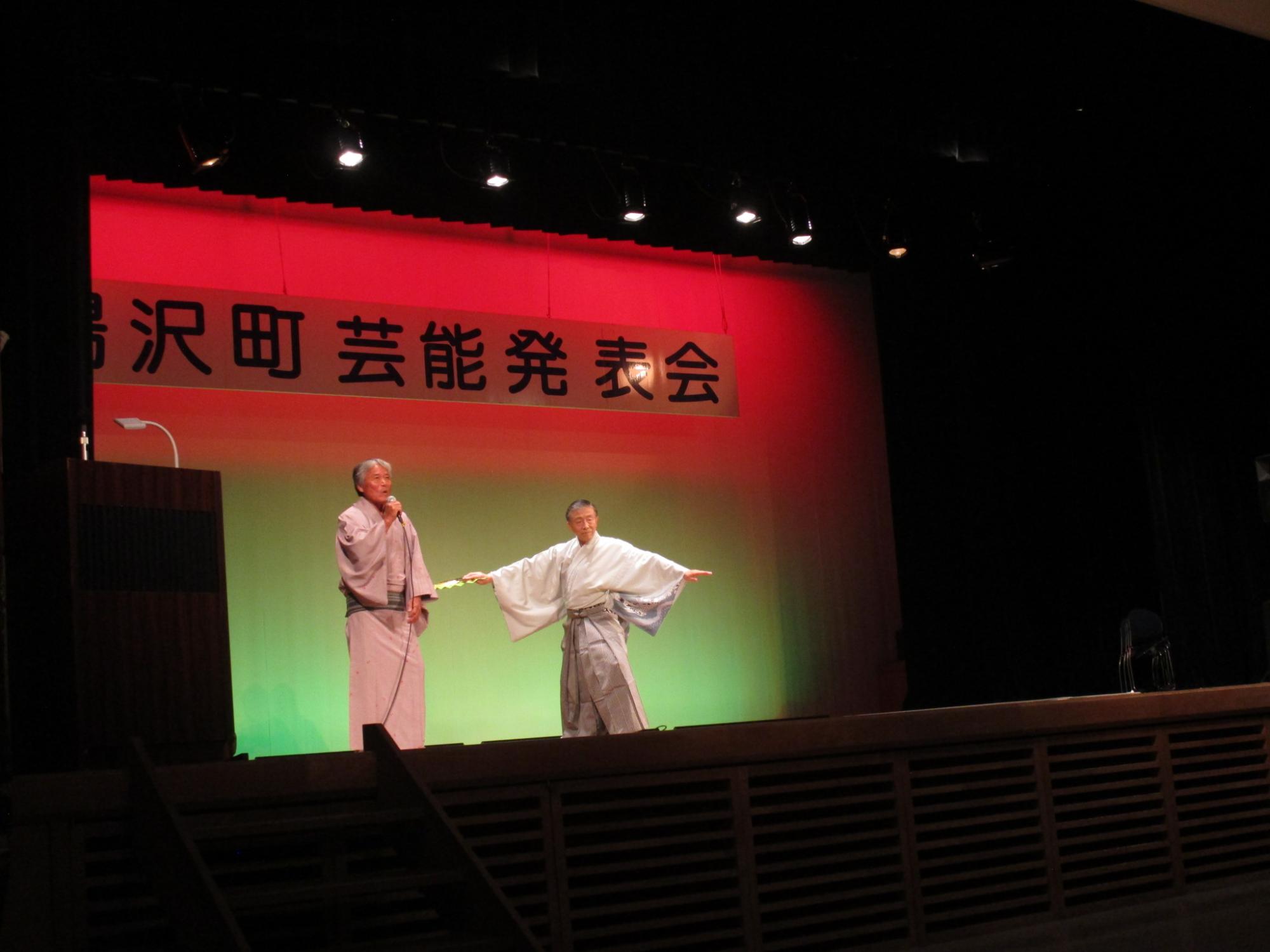 舞台で歌唱・踊る雪国演芸友の会のメンバーの写真