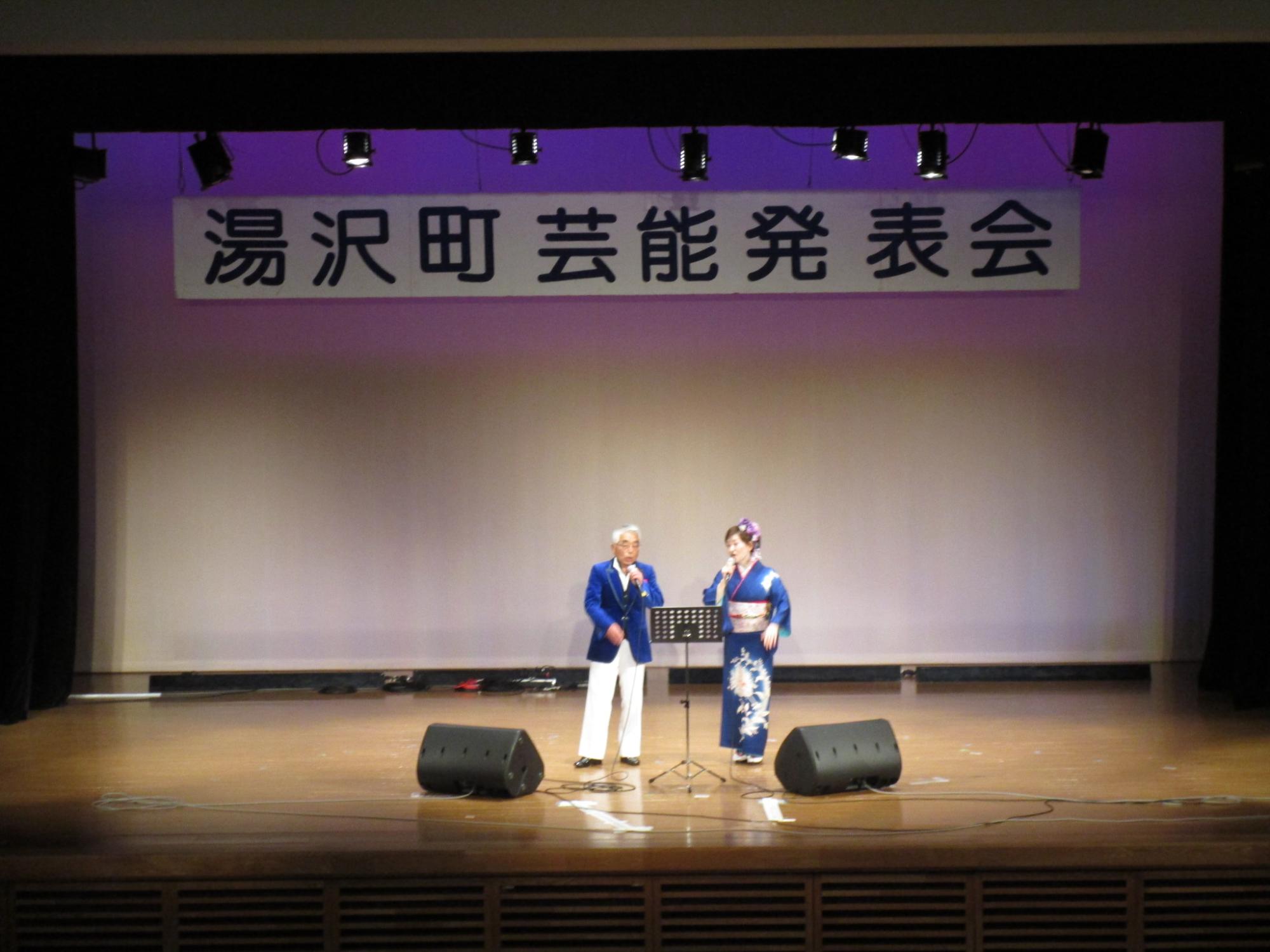 舞台で歌唱する雪国演芸友の会のメンバーの写真