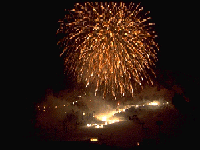 たいまつ滑降と夜空に打ちあがる花火の写真