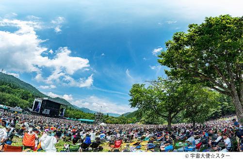 青空の下、会場いっぱいに沢山のお客さんが詰めかけてステージ前に座っている写真