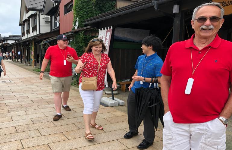 牧之通りを歩いている笑顔のダン・ペイ氏と外国人男女2名と、傘を持った男性の写真